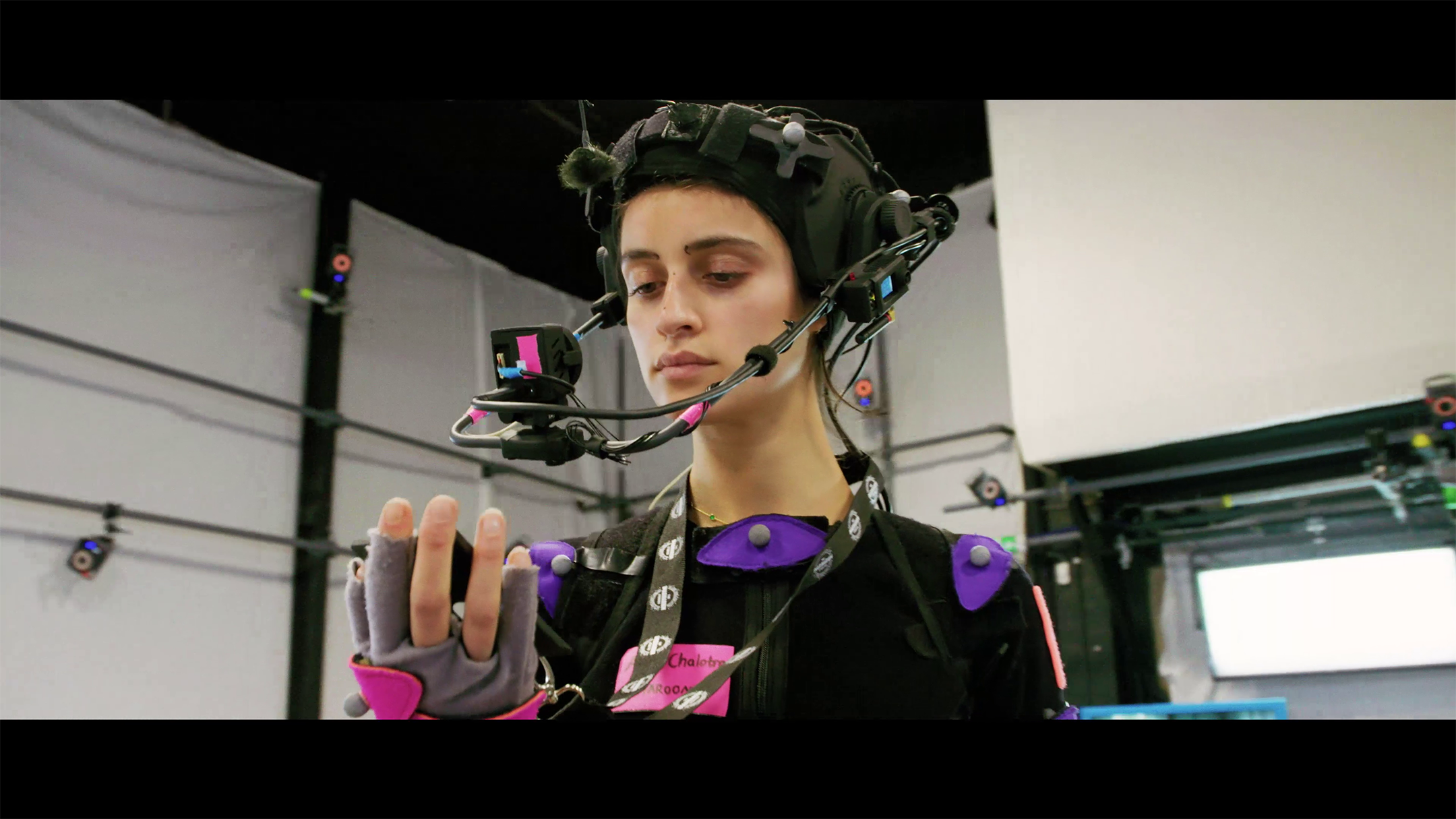 Anya Chalotra in motion capture gear acts out a scene from a trailer.