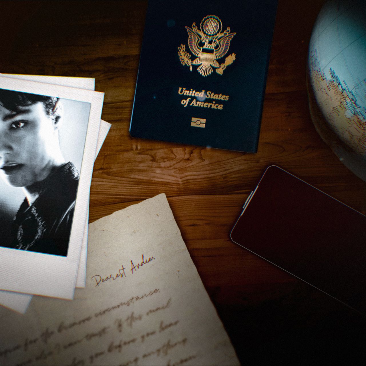 A polaroid photo of Unknown 9: The Genesis Trilogy's Andie Robertson, a handwritten letter, an American passport, a mobile phone, and a globe lie on a wooden table. 